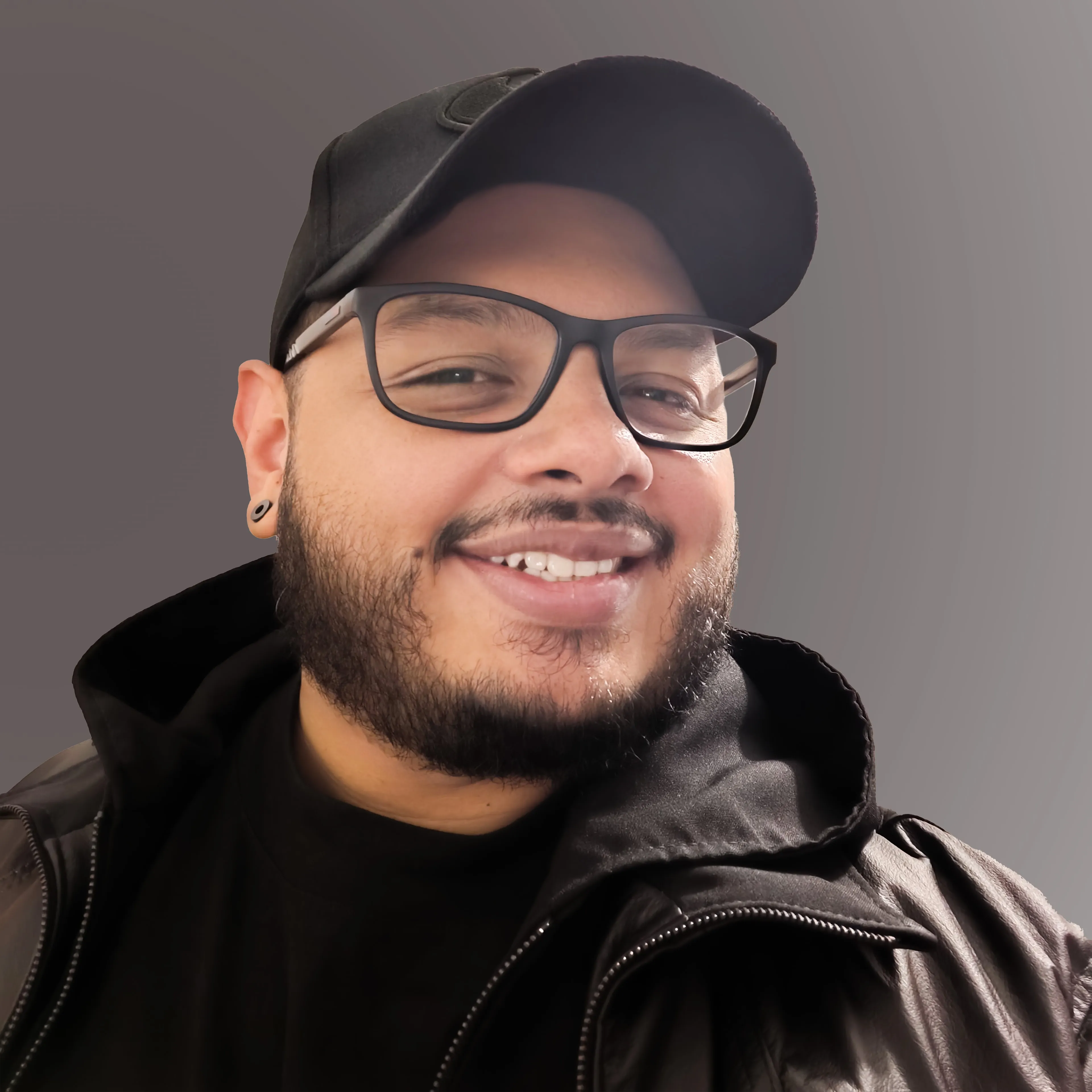 Portrait of Sam Navarro wearing glasses and a dark cap